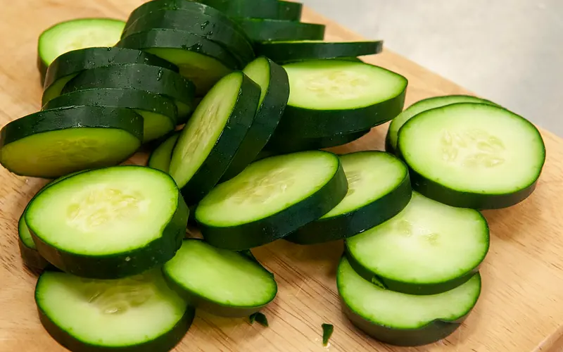 Fresh-cut cucumber slices on a wooden board